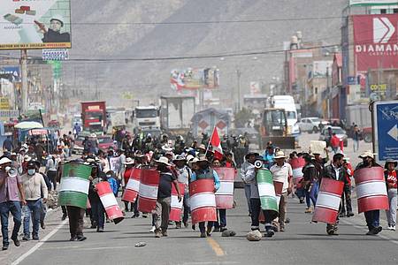 Demonstranten marschieren bei einem Protest gegen die Regierung von Präsidentin Boluarte mit behelfsmäßigen Schildern über eine Straße im peruanischen Arequipa.