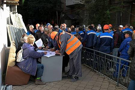 Bauarbeiter stellen sich bei einem mobilen Wahllokal in der von Russland unterstützten und von Separatisten kontrollierten Volksrepublik Donezk an, um ihre Stimmzettel für das Scheinreferendum zu holen.