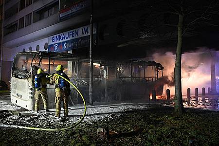 In der Silvesternacht löschen Feuerwehrmänner an der Berliner Sonnenallee einen Reisebus, der von Unbekannten angezündet wurde.