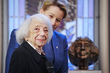 Margot Friedländer mit Berlins Regierender Bürgermeisterin Franziska Giffey vor einer Büste, die Friedländer zeigt.
