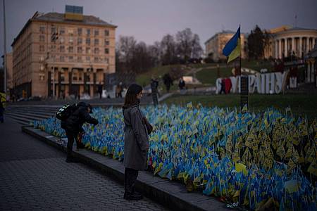 Eine Frau betrachtet ukrainische Flaggen, die zum Gedenken an die Gefallenen des Krieges in der Nähe des Maidan-Platzes im Zentrum von Kiew aufgestellt wurden.