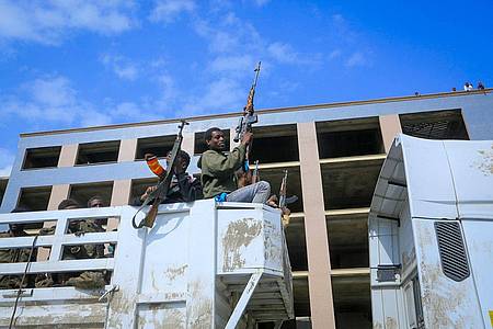 Bewaffnete Tigray-Streitkräfte begleiten gefangene äthiopische Regierungssoldaten und deren verbündete Milizangehörige in offenen Lastwagen auf der Fahrt zu einer Haftanstalt.