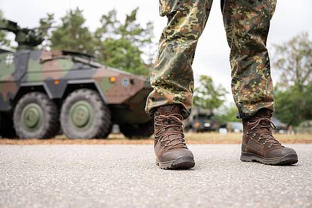 Ein uniformierter Soldat steht vor einem Militärfahrzeug.