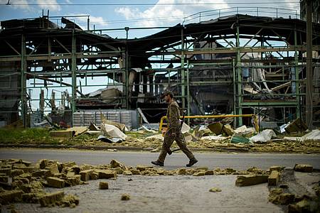 Ein ukrainischer Soldat geht an einer durch Beschuss zerstörten Fabrik vorbei.