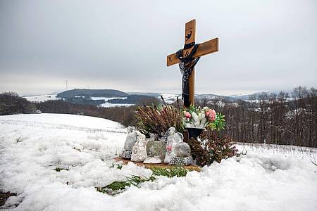 Ein Holzkreuz, Engelsfiguren und Blumen erinnern bei Kusel an die zwei Polizisten, die vor einem Jahr im Dienst getötet wurden.