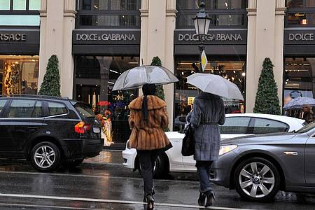 Passanten gehen auf der Maximilianstraße in München an Luxusgeschäften vorbei.