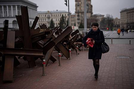 Eine Frau geht in Kiew an Panzersperren vorbei.