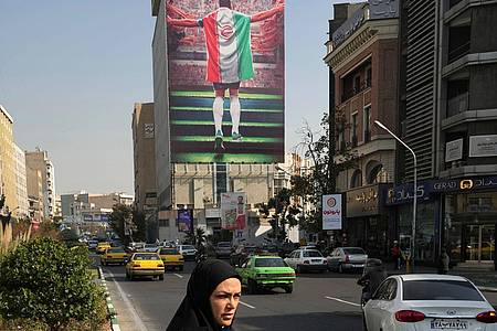 Ein Plakat zeigt einen Fußballspieler mit der Nationalflagge an einem Gebäude in Teheran.