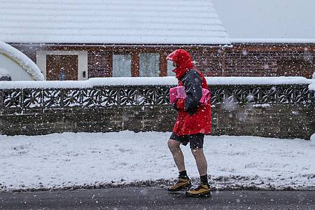Ein Mann geht im nordenglischen  Barnsley bei starkem Schneefall in seinen Shorts spazieren.