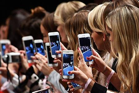 Frauen mit Smartphones dokumentieren die Show des Labels Marc Cain bei der Fashion Week im Jahr 2017.
