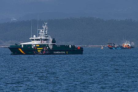 Schiffe der Guardia Civil und des Zolls beteiligen sich an der Bergung eines mutmaßlichen Drogen-U-Boots, von dem nur eine Spitze aus dem Wasser ragt.