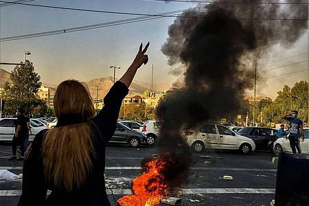 Nach dem Tod der 22-jährigen Mahsa Amini steht eine Frau während einer Demonstration in Teheran vor einem brennenden Autoreifen.