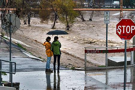 Menschen beobachten die großen Mengen an Regenwasser im Los Angeles River.
