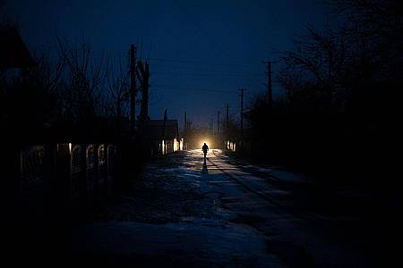 Ein Mann ist während eines Stromausfalls in Kolytschiwka im Scheinwerferlicht eines Autos zu sehen.
