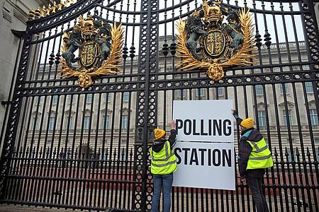 Anhänger der Kampagnengruppe Republic hängen ein Wahllokalschild ans Geländer des Buckingham Palace in London.