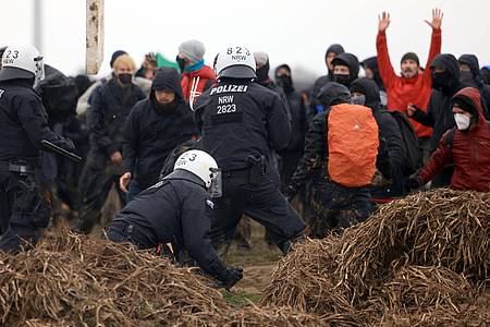 Polizisten und Demonstranten stehen sich am Rande des Braunkohletagebaus bei Lützerath gegenüber.